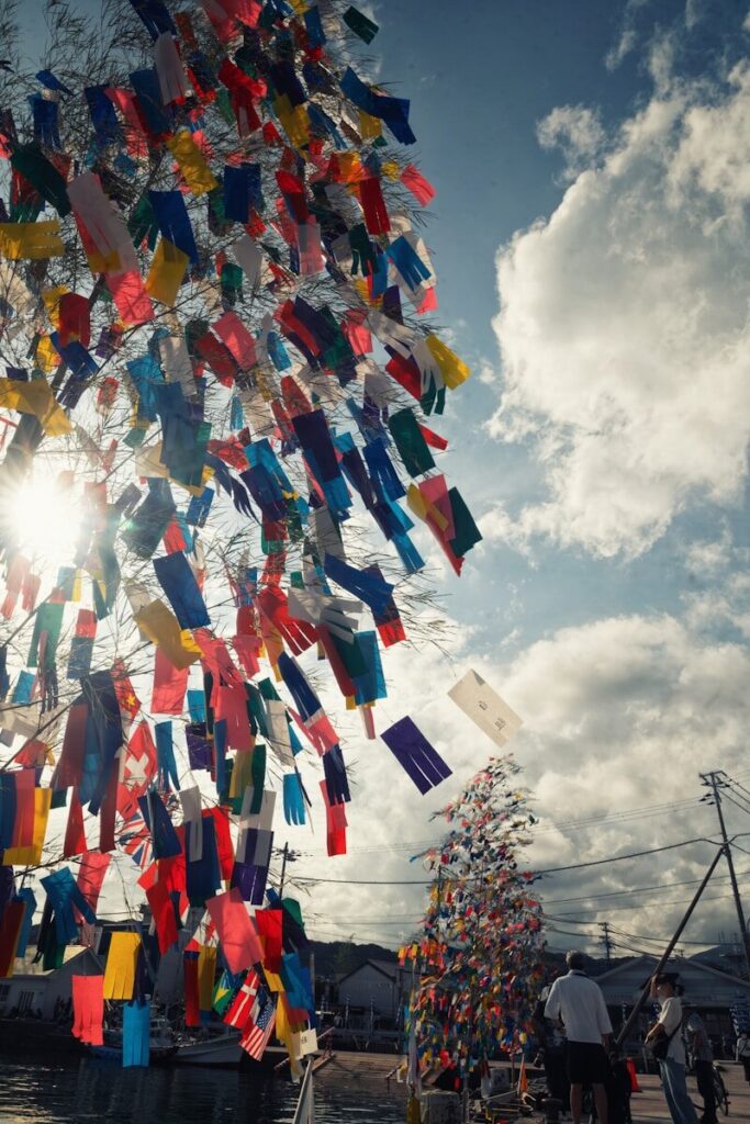 Colorful gloves hanging from tree branches against sky.